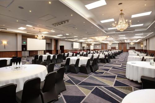 a conference room with white tables and chairs and a podium at Royal National Hotel in London