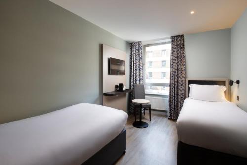 um quarto de hotel com duas camas e uma janela em Royal National Hotel em Londres