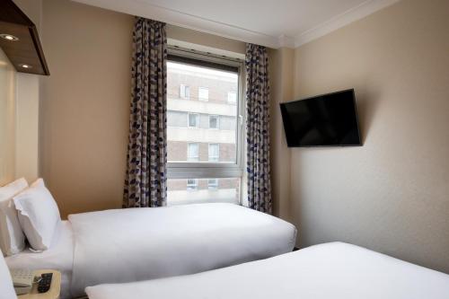 a hotel room with two beds and a window at Royal National Hotel in London