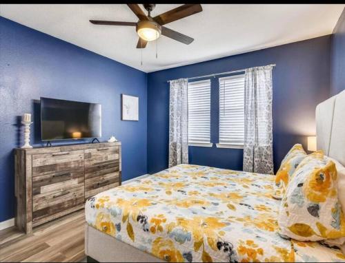 a blue bedroom with a bed and a tv at Beachfront Envy in Galveston