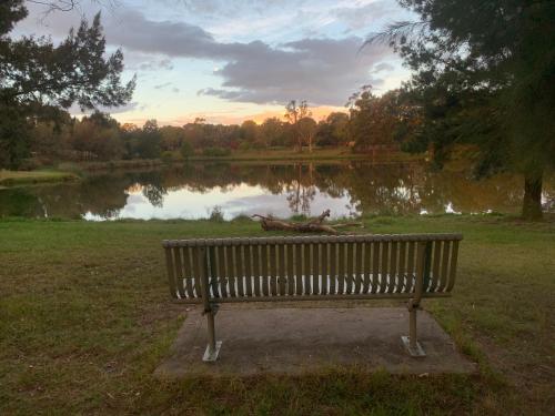a park bench sitting in front of a lake at Tuggeranong Village in Tuggeranong