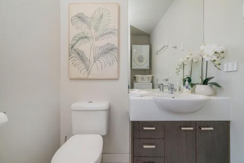 a bathroom with a white toilet and a sink at Aqua Soleil Villas in Whitianga