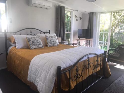 een slaapkamer met een groot bed met kussens erop bij Orange Tree Cottage - garden hideaway in Whanganui