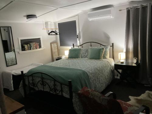 a bedroom with a bed with a green comforter at Orange Tree Cottage - garden hideaway in Whanganui