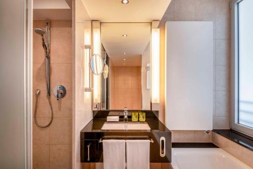 bagno con lavandino, vasca e specchio di Four Points by Sheraton Munich Arabellapark a Monaco