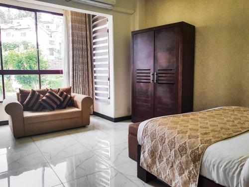 a bedroom with a bed and a couch and a large window at Galaxy City Hotel in Kandy