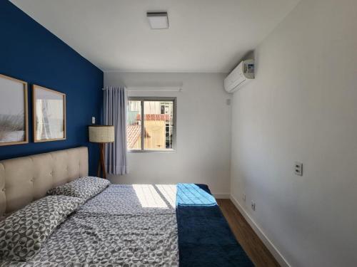um quarto com uma cama com uma parede azul em Charmoso apartamento perto da praia em Vitória