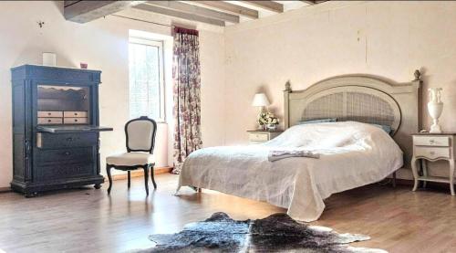 a bedroom with a large bed and a chair at La Maison bleue in Varzy