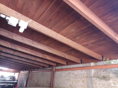 a wooden ceiling in a garage with a car parked under it at Descanso Los Alamos in Plottier