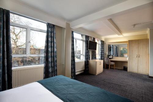 a hotel room with a bed and a desk and window at Bedford Hotel in London