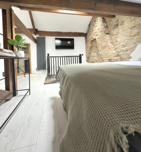 a bedroom with a large bed and a stone wall at Farsley Cottage in Farsley