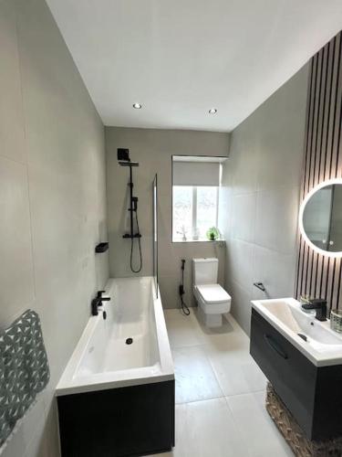 a bathroom with a tub and a sink and a toilet at Farsley Cottage in Farsley