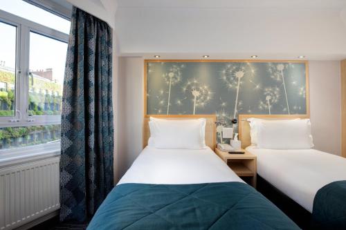 two beds in a room with a window at Bedford Hotel in London