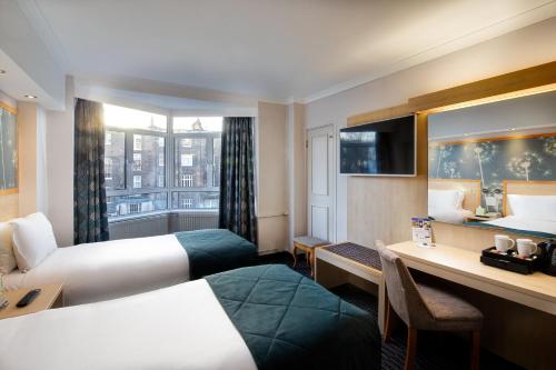 a hotel room with two beds and a desk at Bedford Hotel in London