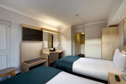 a hotel room with two beds and a desk at Bedford Hotel in London