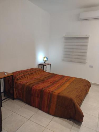 Schlafzimmer mit einem Bett, einem Schreibtisch und einem Fenster in der Unterkunft Lomas del Mirador in San Fernando del Valle de Catamarca
