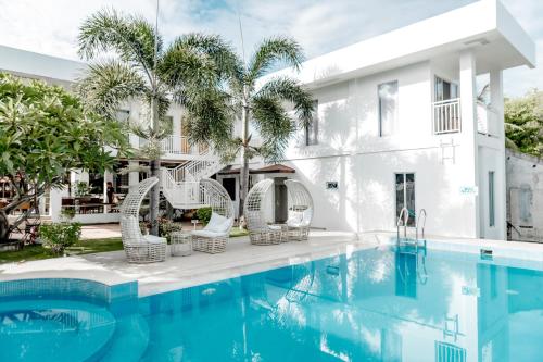 a swimming pool with wicker chairs next to a building at A Villas Resort & Restaurant in Zamboanguita