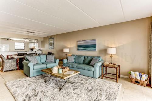 a living room with two blue couches and a table at Amelia The Sea - 558 ASea in Fernandina Beach