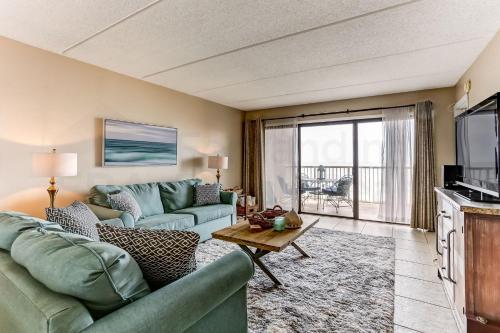 a living room with two green couches and a television at Amelia The Sea - 558 ASea in Fernandina Beach