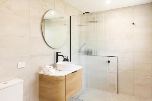 a bathroom with a shower and a sink and a mirror at Hermitage Lodge in Pokolbin