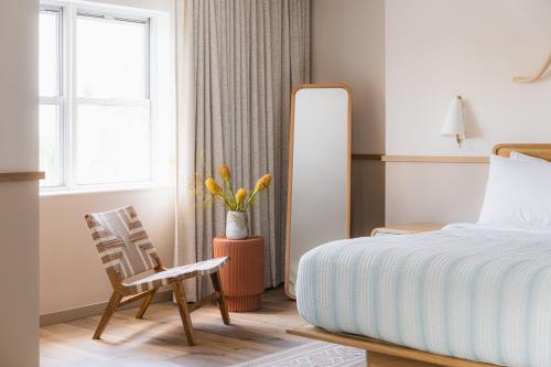 a bedroom with a bed and a chair and a mirror at The Ryder Hotel in Charleston