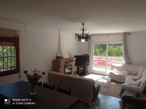 ein Wohnzimmer mit einem Sofa, einem Tisch und einem TV in der Unterkunft Casa Calafell in Segur de Calafell