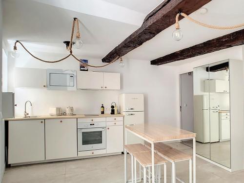 une cuisine avec des armoires blanches et une table en bois dans l'établissement Studio 7b classé 3 étoiles climatisé à 2 mn du Port byLaConciergerie13, à La Ciotat