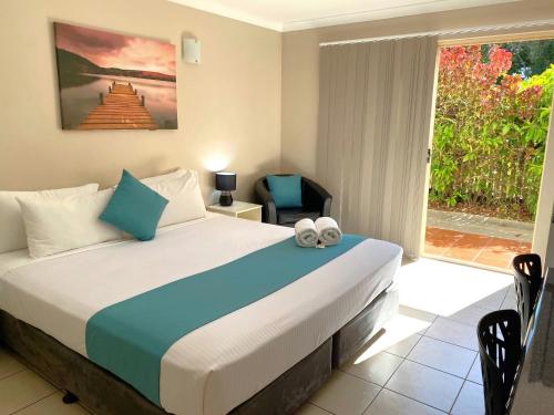 um quarto com uma cama, uma cadeira e uma janela em City Ville Apartments and Motel em Rockhampton