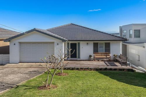 a white house with a bench on a deck at Amaroo in Gerroa