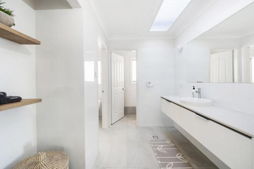 a white bathroom with a sink and a mirror at Amaroo in Gerroa
