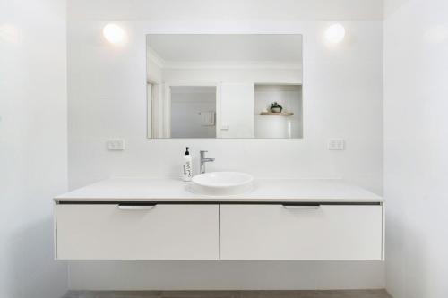 uma casa de banho branca com um lavatório e um espelho em Amaroo em Gerroa