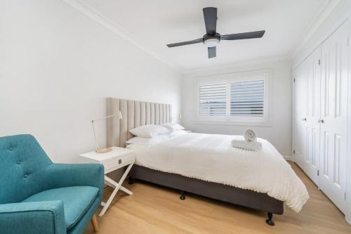 a bedroom with a bed and a blue chair at Amaroo in Gerroa