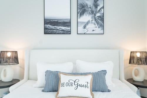 a bedroom with a white bed with two pictures on the wall at ~Spacious home near beach w/ game room and community pool~ in Orange Beach
