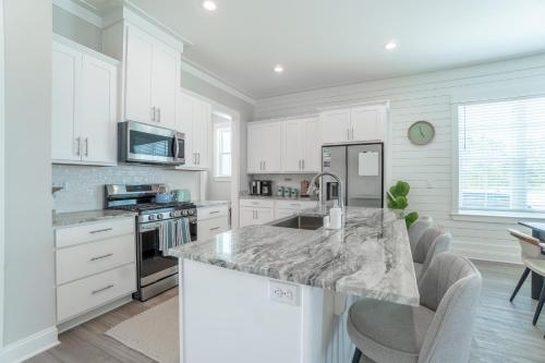 a kitchen with white cabinets and a marble counter top at ~Spacious home near beach w/ game room and community pool~ in Orange Beach