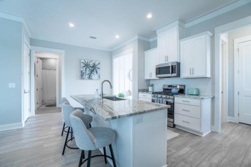 a kitchen with white cabinets and a counter with stools at ~Spacious home near beach w/ game room and community pool~ in Orange Beach