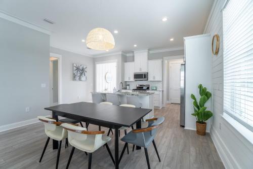 a dining room with a black table and chairs at ~Spacious home near beach w/ game room and community pool~ in Orange Beach