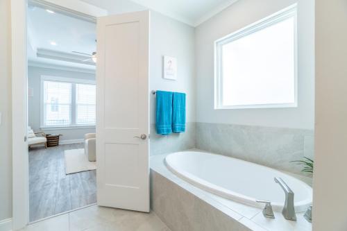 a white bathroom with a tub and a window at ~Spacious home near beach w/ game room and community pool~ in Orange Beach