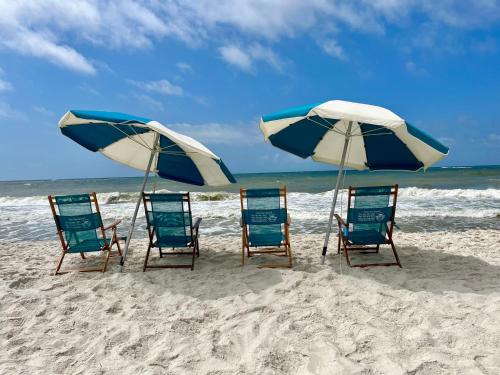 a group of chairs and umbrellas on a beach at ~Spacious home near beach w/ game room and community pool~ in Orange Beach