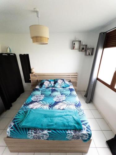 フォール・ド・フランスにあるKayChouchou- Appart cosy au cœur de Fort-de-Franceのベッドルーム1室(青と白のシーツが備わるベッド1台付)