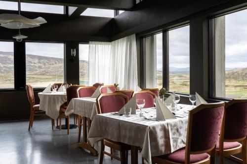 a dining room with tables and chairs and windows at Dalahótel in Laugar