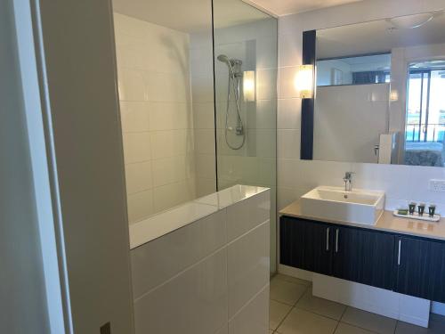 a white bathroom with a sink and a shower at Exclusive Apartment with Ocean Views in Caloundra