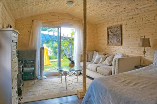 een slaapkamer met een bed, een bank en een tafel bij Gather-on-Trent, Your Private Waterfront Luxury Resort in Trent Hills in Campbellford