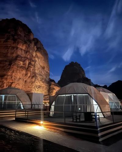 two domes in front of a mountain at night at RUM FLORAA LUxURY CAMP in Wadi Rum