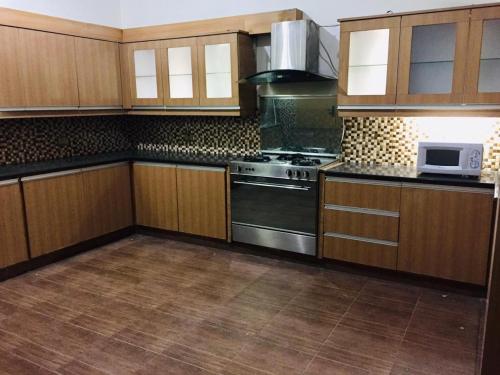 a kitchen with wooden cabinets and a stove top oven at Islamabad Residency 2 in Islamabad
