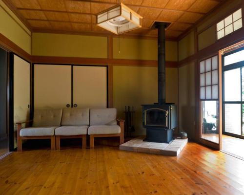 a living room with a couch and a wood stove at Asama Vista quiet home with view, Foreign Hosts in Miyota