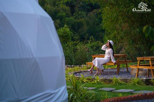 a woman is sitting on a bench at Orchard Home Nam Cat Tien in Cat Tien