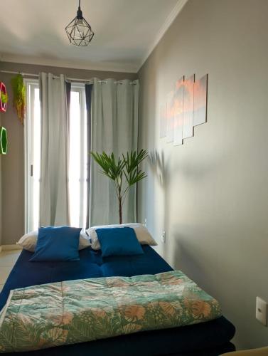 ein Schlafzimmer mit einem Bett mit blauen Laken und einer Pflanze in der Unterkunft Cantinho Verde in Santa Maria
