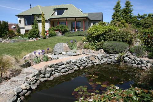 un ponte sopra un laghetto di fronte a una casa di Esther Lodge - Lake Tekapo a Lake Tekapo