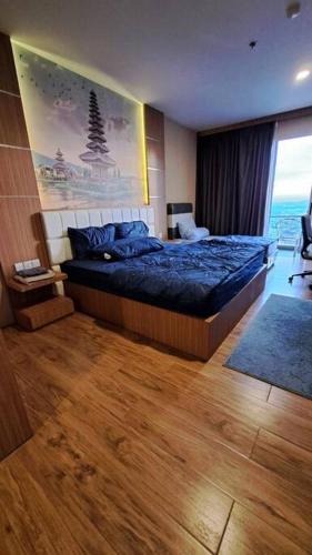 una camera da letto con un letto con un piumone blu e una finestra di Apartment Pelita Batam Floor 21 no 9 Studio with Balcony a Nagoya