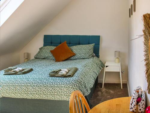 a bedroom with a bed with a blue headboard and a table at No, 2 Badger Sett-uk44307 in Lenwade